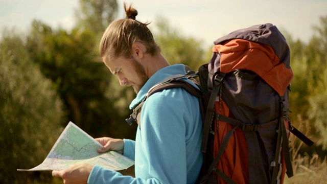 一个年轻的白种人手里拿着一张地图在登山旅行。视频素材