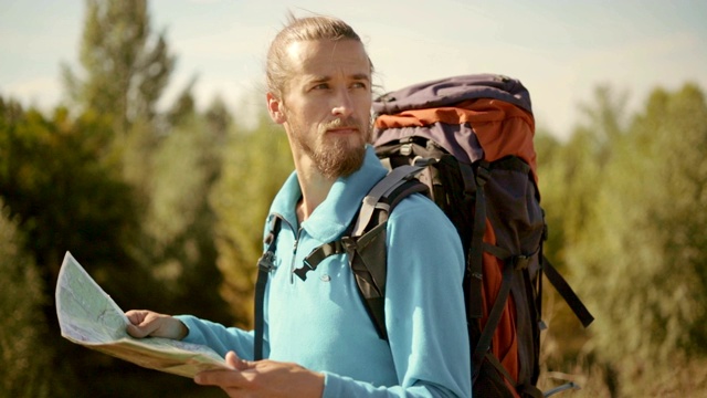 一个年轻的白种人手里拿着一张地图在登山旅行。视频素材