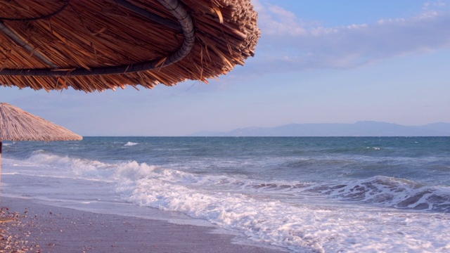 海景海洋和美丽的海景热带海滩透过茅草伞。空旷的沙滩上的背景清澈的绿松石海。节日的概念视频素材