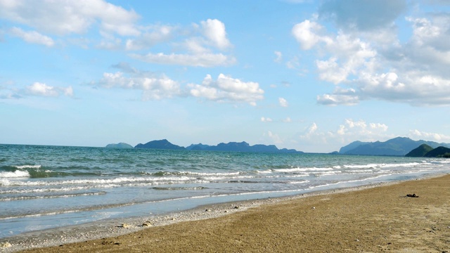 海浪拍打着棕色的沙滩，蓝天白云视频素材