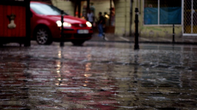 雨中的欧洲城市抽象镜头。专注于落下的雨滴。汽车和行人的街道散焦了视频素材