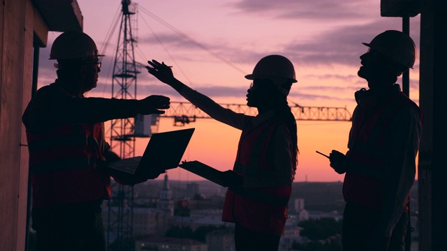 一群工程师正在夕阳西下的建筑工地谈话视频素材