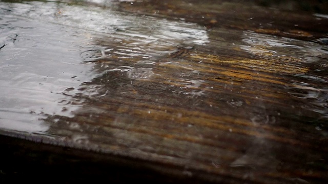 水以慢动作滴在木板上。旧木头被雨淋湿了。视频素材