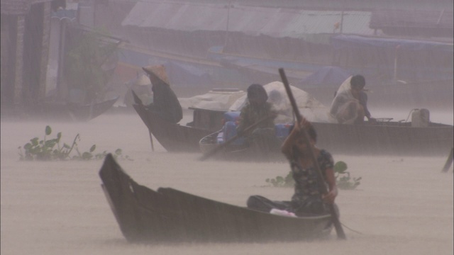 柬埔寨河边的村民在大雨中划着船过河。视频素材