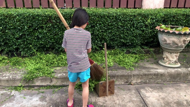 全家在一起做家务，女孩在清扫树叶视频素材