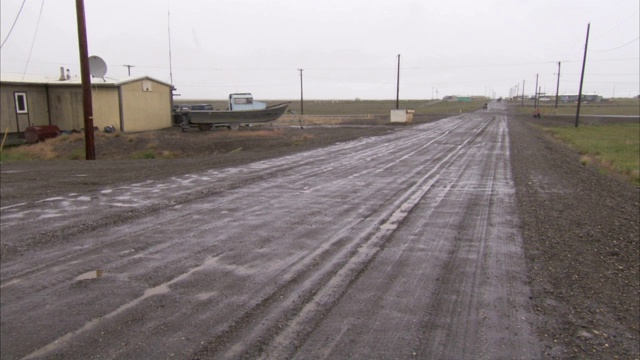 一条泥泞的道路经过阿拉斯加小镇上的一些小房子。视频素材