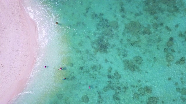 鸟瞰图美丽的曲线海滩与旅客放松与翡翠海。视频素材