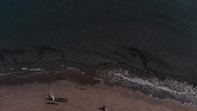 飞过沙滩，看着平静的海浪拍打着沙滩。视频下载