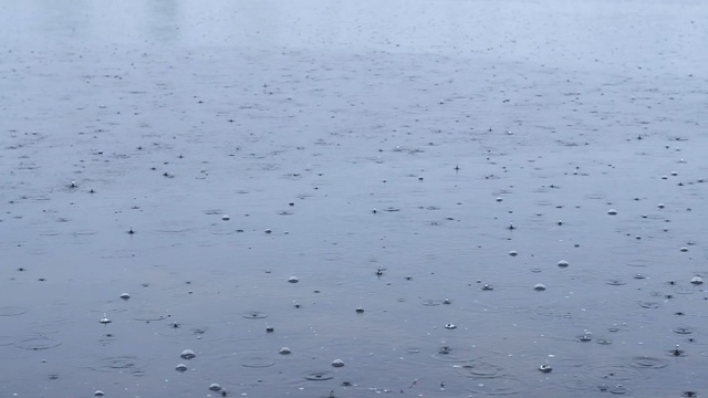 雨季的雨滴落在河流上，倾泻的雨水撞击水面的图案，移动的纹理背景视频素材