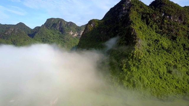 无人机从雾气中飞过，飞向被照亮的群山视频素材