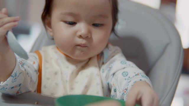 小女孩在家里的客厅里吃着妈妈喂给她的食物。视频素材