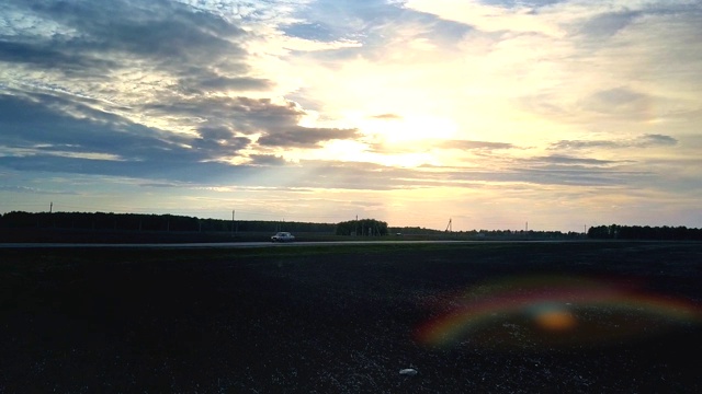 夕阳的光芒从云层后面照耀在道路和田野上视频素材