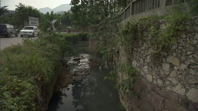 车辆驶过一条被污染的运河和河流。视频素材