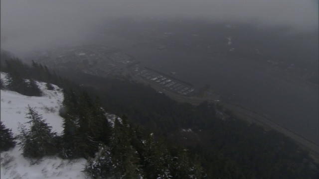 雾弥漫在森林覆盖、白雪皑皑的高山和山谷之上。视频素材