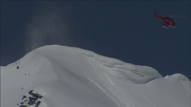 一架救援直升机在积雪覆盖、雪崩频发的山顶上空盘旋。视频素材