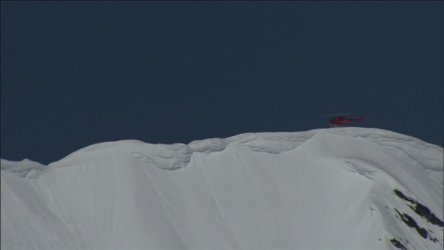 一架救援直升机飞过积雪覆盖、雪崩频发的山峰。视频素材