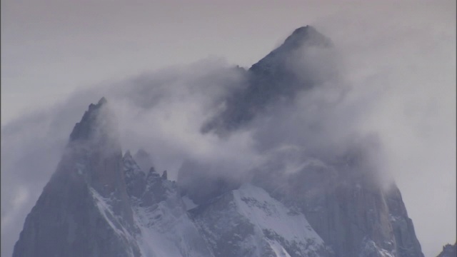 稀薄的流云覆盖着参差不齐的雪山山顶。视频素材