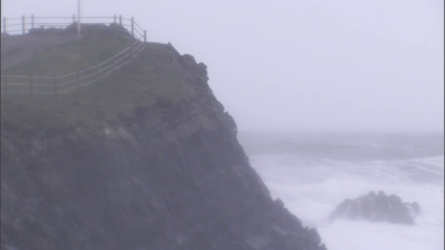 汹涌的海浪冲击着多岩石的海岸，带来阵阵薄雾。视频素材