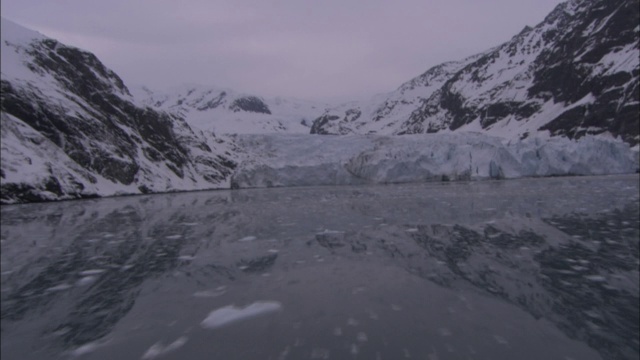 平静而冰冷的海水反射着白雪覆盖的冰川。视频素材