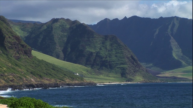 海浪冲刷着夏威夷郁郁葱葱、多山的海岸。视频素材