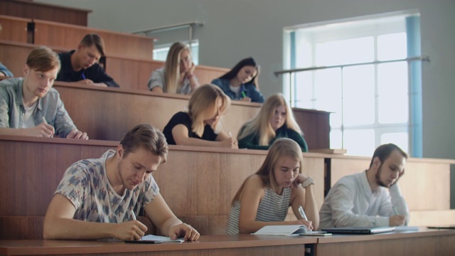 当讲师给满教室的学生讲课时，他的手。年轻人在大学里听讲座视频素材