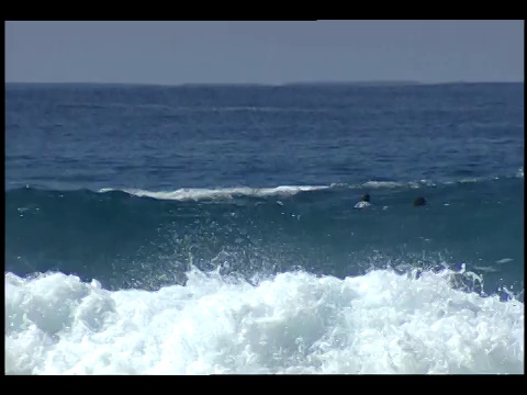 冲浪者在翻滚的海浪上骑着冲浪板。视频素材