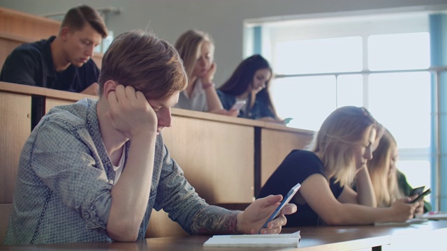 在一场无聊的大学讲座中，学生们看着智能手机的屏幕。许多人视频素材