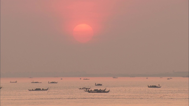 在玫瑰色的夕阳下，独木舟在湄公河上游弋。视频素材