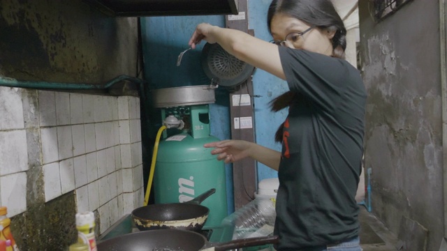 亚洲年轻女孩准备混合意大利食物烹饪黑色意大利面与鱼，拍摄膳食与移动相机。视频素材