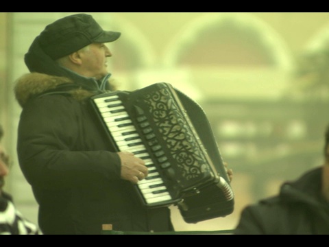 一位音乐家演奏手风琴，为在户外咖啡馆用餐的人们唱歌。视频素材