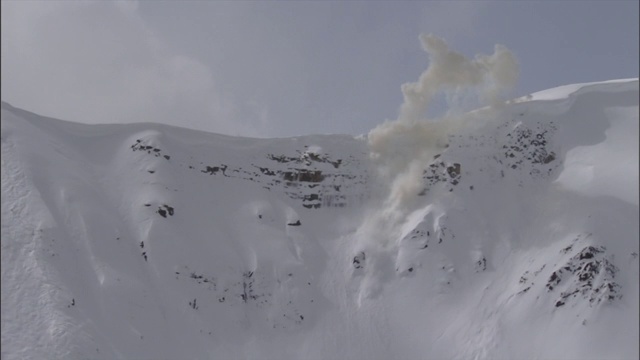 爆炸引发雪崩，使雪从山坡上滑下来。视频素材