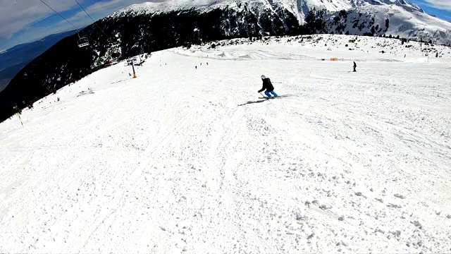 跟踪专业运动滑雪者在高山滑雪度假村的山上滑雪道，电影慢动作POV视频素材