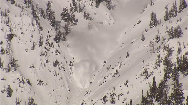 爆炸在白雪皑皑的山坡上造成雪崩。视频素材