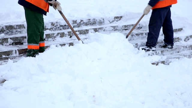 工人们用铁锹清除城镇广场楼梯上的积雪。视频素材