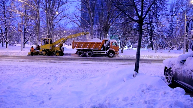 近距离观察扫雪机的工作过程。扫雪机将雪装入卡车体内。视频素材