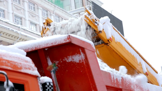 近距离观察扫雪机的工作过程。扫雪机将雪装入卡车体内。视频素材