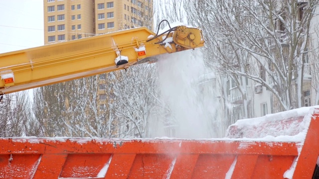 近距离观察扫雪机的工作过程。扫雪机将雪装入卡车体内。视频素材