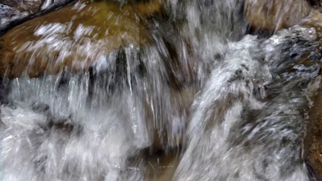 水流过石头被河水冲刷过的巨石天然岩石上惊人的瀑布水流湍急视频素材