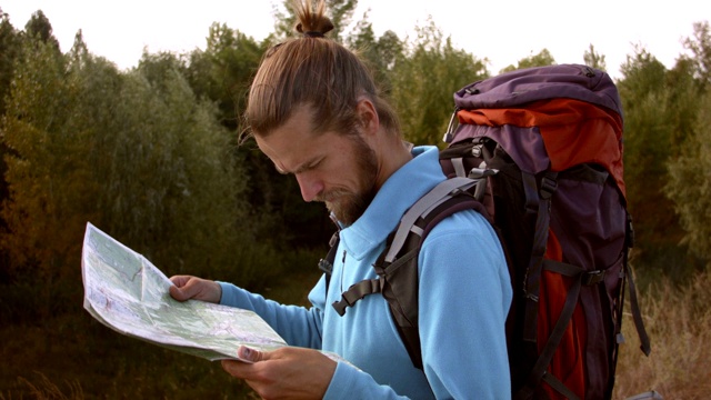 一个年轻的白种人手里拿着一张地图在登山旅行。视频素材