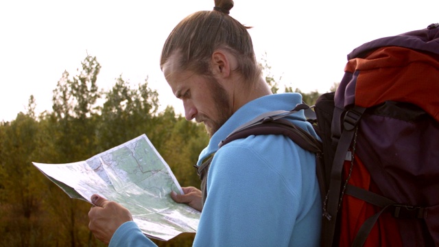 一个年轻的白种人手里拿着一张地图在登山旅行。视频素材