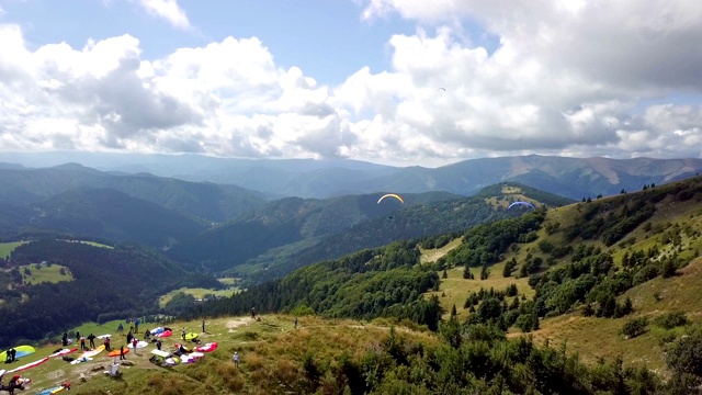 空中滑翔伞起飞与飞行滑翔伞在山区景观鸟瞰图视频素材