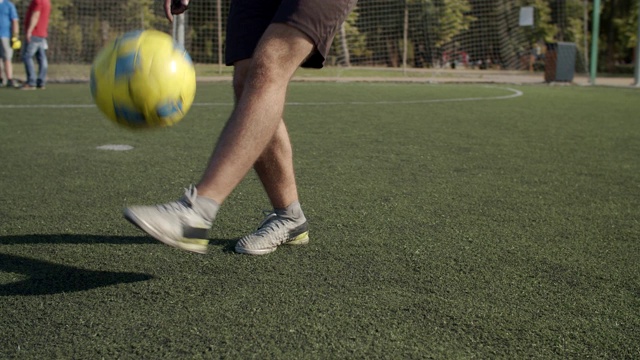 足球运动员的腿在球场上弹跳球视频素材