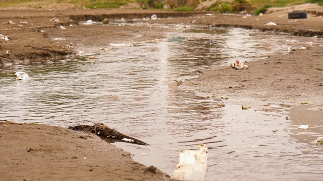 3 . A shot of A small canal of waste flows through the sand beach to the sea .一小段废物的运河穿过沙滩流向大海视频素材