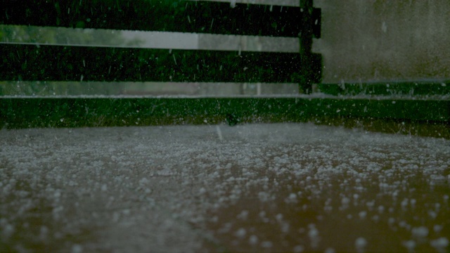 特写:雨点和软冰雹落在潮湿的门廊上，溅起静止的水视频素材