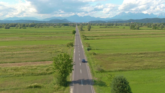 航拍:深蓝色的自动驾驶汽车在笔直的乡村道路上行驶。视频素材