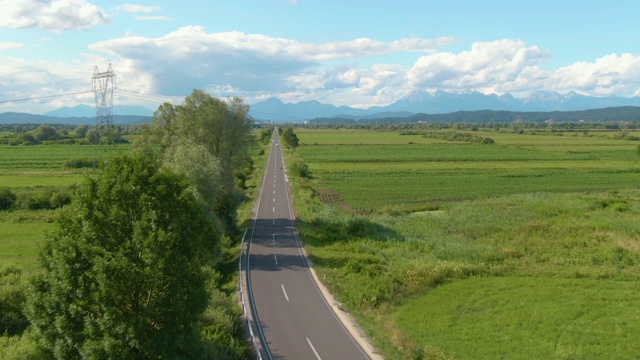 空中摄影:飞过一条笔直的柏油路，穿过风景优美的乡村视频素材