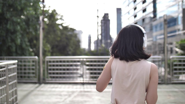 迷人的女孩用智能手机耳机听音乐的慢镜头视频素材