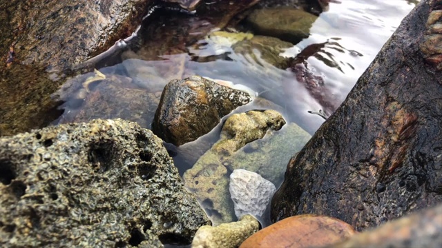 海水拍打着岩石，石头近距离反射着光线视频素材