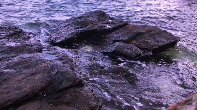 海水拍打着岩石，石头近距离反射着光线视频素材