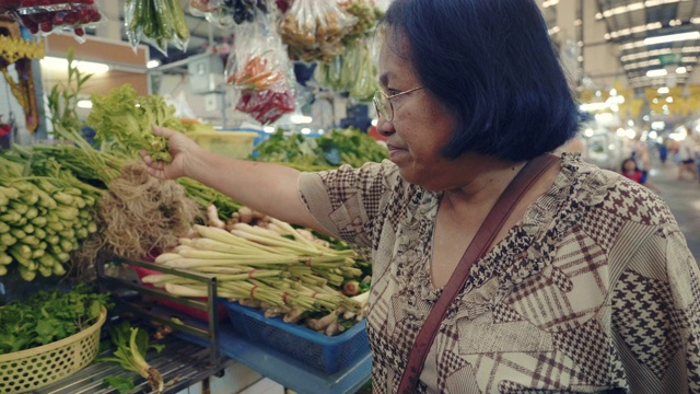 一位年长的亚洲妇女在农贸市场买菜视频素材